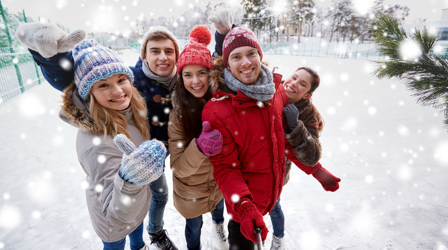 Groupe de collaborateurs d'âges variés en tenue décontractée professionnelle patinant ensemble sur une patinoire synthétique mobile lors d'un team building en intérieur, certains se tenant par le bras, dans une ambiance conviviale et souriante